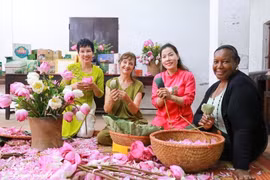 Los turistas experimentan la artesanía tradicional de infusionar té con flores de loto de Quang An. (Foto: VNA)