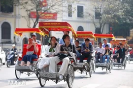 Turistas extranjeros experimentan un recorrido en triciclo alrededor del lago Hoan Kiem en Hanói (Foto: VNA)