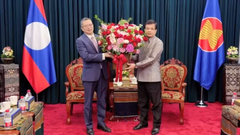El embajador vietnamita en China, Pham Thanh Binh, entrega flores a su par de Lao, Somphone Sichaleun.