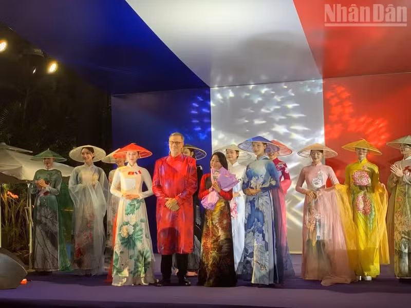 El embajador francés Olivier Brochet felicita a la diseñadora y a las modelos que presentaron una colección de Ao dai durante el evento.