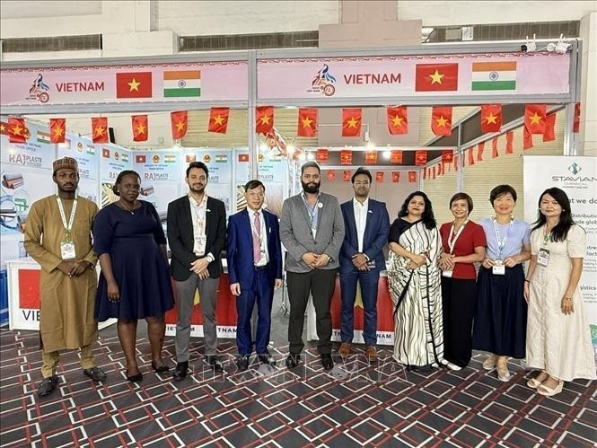 El consejero comercial Bui Trung Thuong (cuarto desde la izquierda) posa para una foto con invitados nacionales e internacionales que visitan el stand. (Foto: VNA)