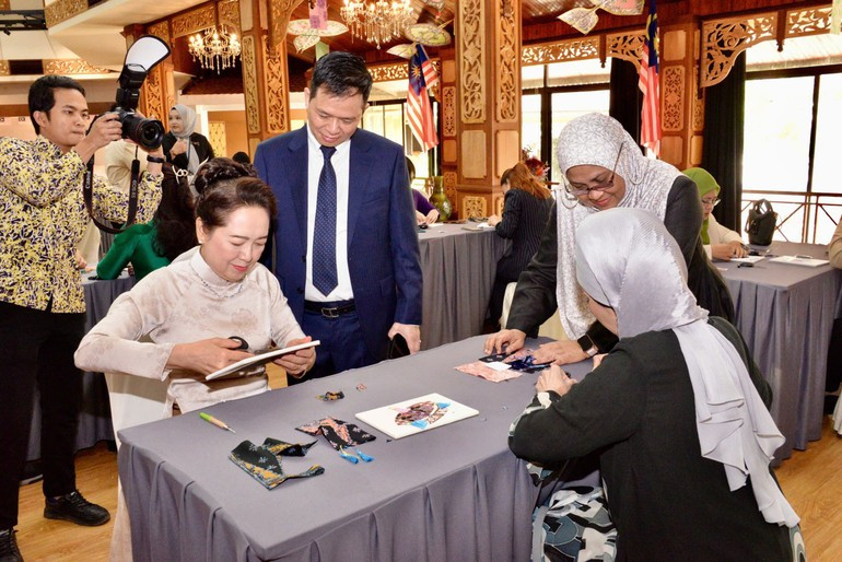 Nguyen Thi Thanh Nga, esposa del presidente del Parlamento de Vietnam y Rozana bintin Kamal, esposa del presidente de la Cámara de Representantes de Malasia, experimentan la impresión tradicional de telas. (Foto: Nhan Dan)