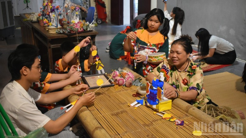 La artesana Nguyen Thi Tuyen presenta muñecos del “doctor de papel” a los jóvenes.