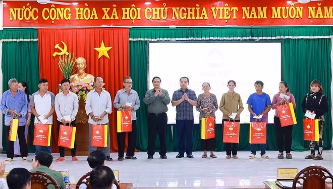 El primer ministro Pham Minh Chinh entrega obsequios a las familias beneficiarias de políticas sociales en la comuna de De Gi (Foto: VNA)