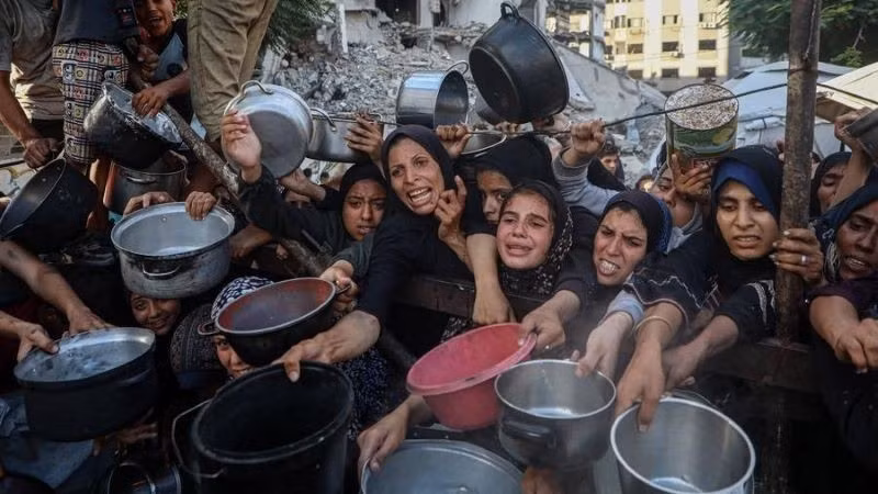 Palestinos desplazados esperan alimentos en un centro de distribución en la ciudad de Gaza, el 14 de julio de 2025. (Foto: Xinhua)