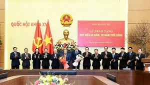 El presidente de la Asamblea Nacional, Tran Thanh Man, y funcionarios felicitan a Duong Thanh Binh y Phung Khanh Tai (con flores) por la concesión de las insignias de 45 y 30 años de membresía del Partido. (Foto: Nhan Dan)