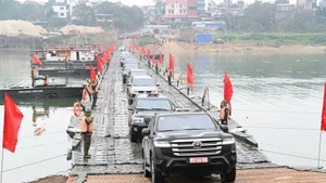 Personas y vehículos circulan con normalidad a través del puente flotante sobre el río Lo en la mañana del 16 de febrero. (Foto: qdnd.vn)