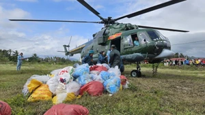 Un helicóptero militar lanza suministros de socorro a una zona afectada por las inundaciones. (Foto: Nhan Dan)