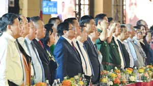 Los delegados saludan a la bandera nacional en el programa. (Foto: Nhan Dan)