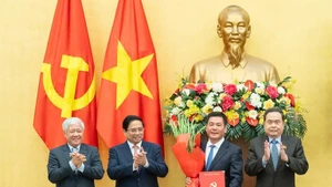 El primer ministro Pham Minh Chinh (segundo desde la izquierda) y el presidente de la Asamblea Nacional Tran Thanh Man (extrema derecha), entregan la decisión del nombramiento y ofrecen flores a Nguyen Hong Dien. (Foto: Nhan Dan)