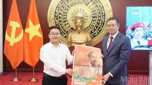 El representante de la corresponsalía del periódico Nhan Dan en China entrega el suplemento especial al embajador de Vietnam en Pekín, Pham Thanh Binh.