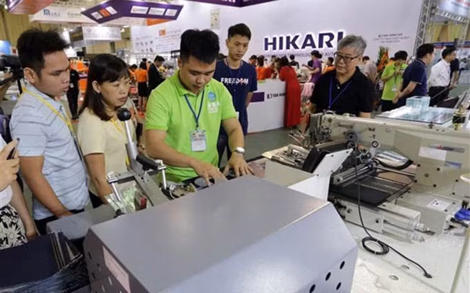 Visitantes recorren en una exposición de equipos y maquinarias de confección textil en Vietnam (Fuente: VNA)