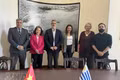 La embajadora Ngo Minh Nguyet (de traje magenta) y el alcalde interino de Montevideo, Justo Onandi (tercero desde la izquierda), junto con representantes de las autoridades locales, posan para una foto tras una sesión de trabajo. (Foto: VNA)