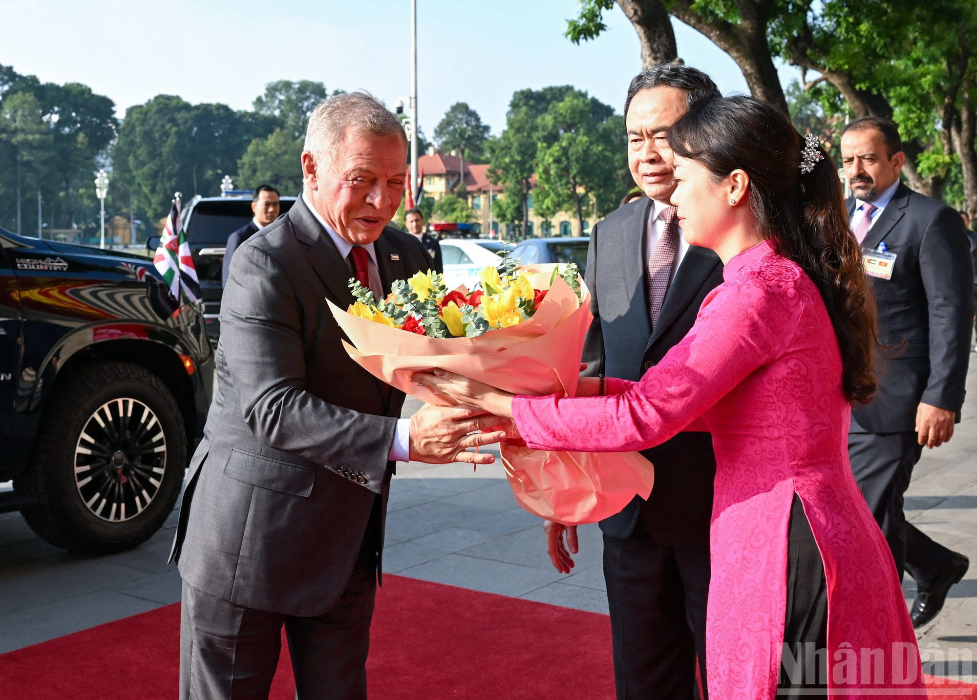 Personal de la Oficina de la Asamblea Nacional entrega flores para dar la bienvenida al rey de Jordania.