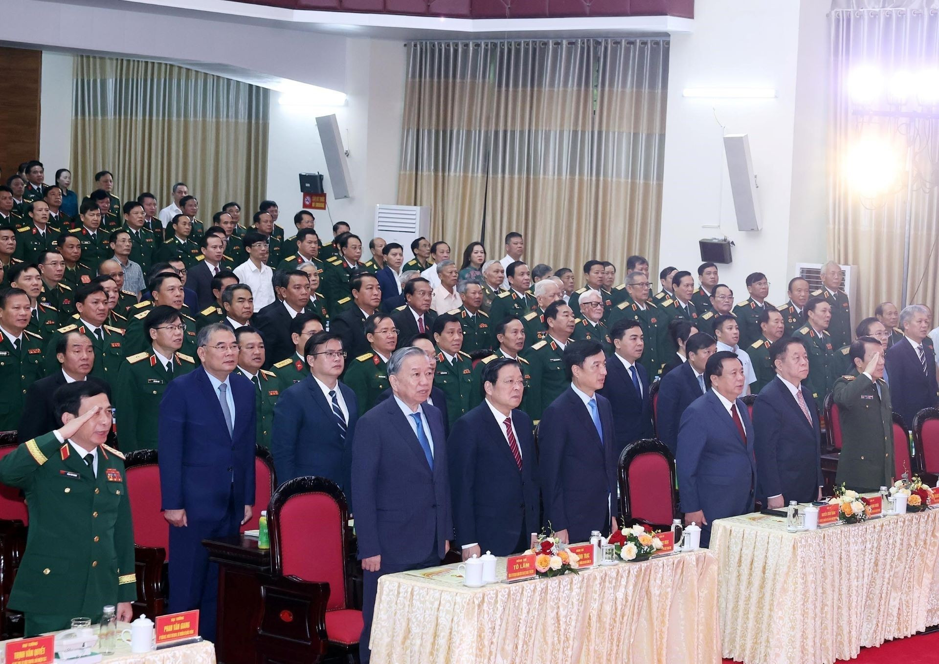 Los asistentes realizan el acto de saluda a la bandera.