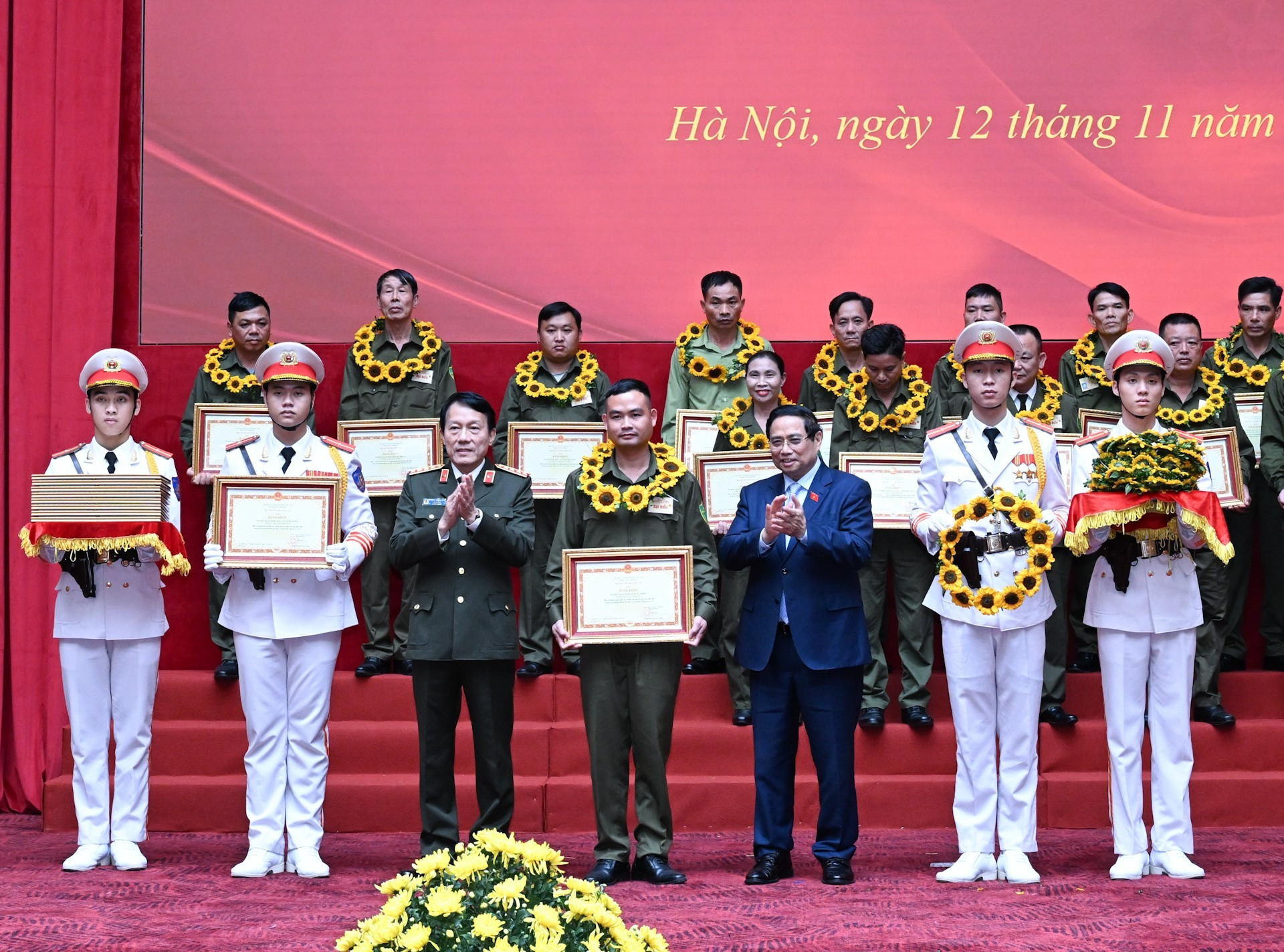 El premier Pham Minh Chinh y el ministro de Seguridad Pública, Luong Tam Quang, entrega certificados de mérito a colectivos e individuos destacados.