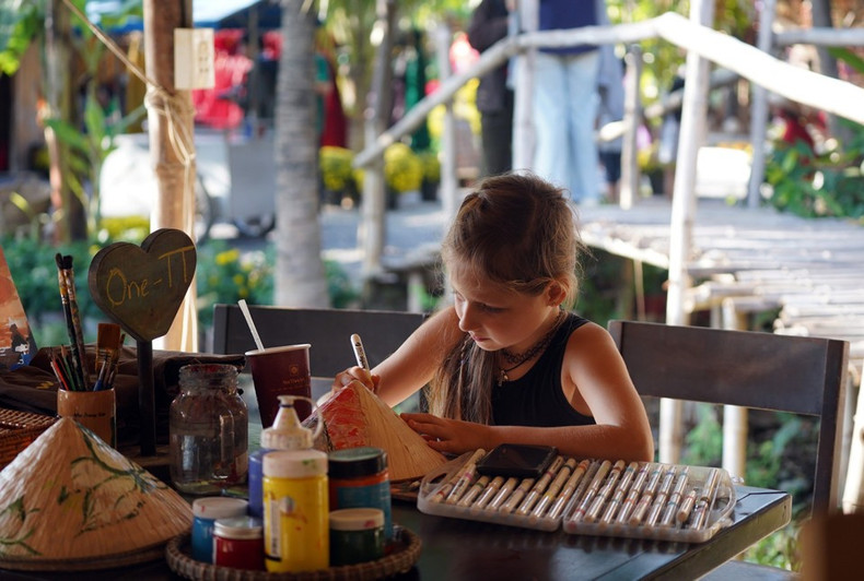 Niños extranjeros escriben caligrafía en un espacio dedicado a las tradicionales celebraciones del Tet en el pasado.