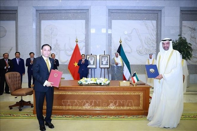 Los dos primeros mnistros presencian la ceremonia de firma del Protocolo que modifica el Acuerdo de Exención de Visado para Pasaportes Diplomáticos y Oficiales y el Memorando de Entendimiento entre la Academia Diplomática de Vietnam y el Instituto Diplomático Saud Al-Nasswe Al-Sabah de Kuwait. (Foto: VNA)