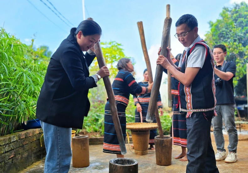 Los turistas experimentan el proceso de machacar arroz en la ceremonia.