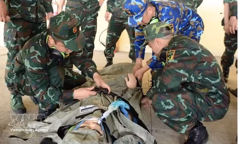 Los miembros del equipo AMET practican la recepción y sujeción de un paciente en una camilla para su traslado a una ambulancia (Foto: VNA)