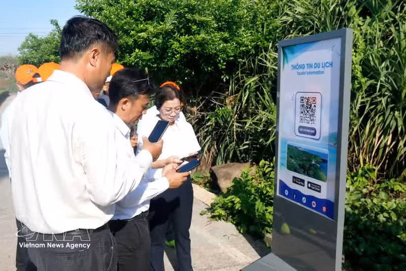 Un turista escanea un código QR para acceder rápidamente a la información turística en el mástil de la bandera de soberanía de la zona especial de Phu Quy (Lam Dong). (Foto: VNA)