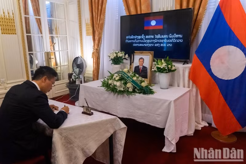 El encargado de negocios interino Pham Quang Anh firma el libro de condolencias en memoria de Saysomphone Phomvihane. (Foto: Khai Hoan).