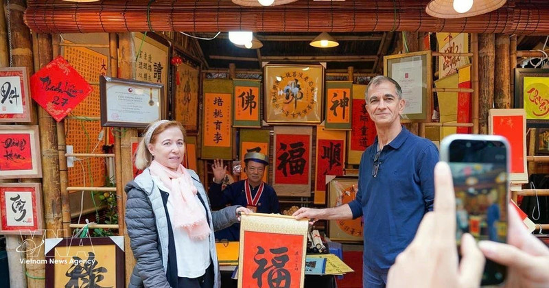 Los turistas internacionales disfrutan de la tradición de recibir caligrafía auspiciosa a principios de año. (Foto: VNA)