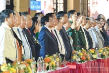 Los delegados saludan a la bandera nacional en el programa. (Foto: Nhan Dan)