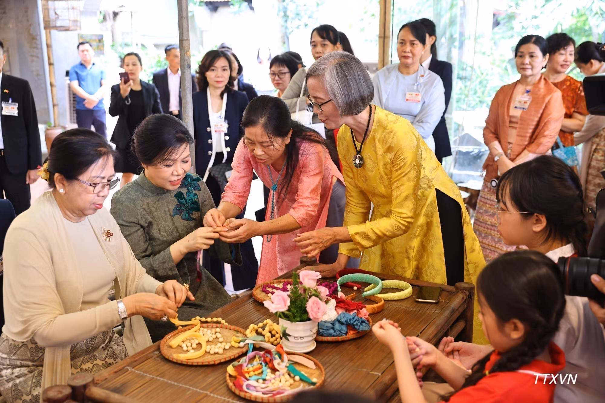 Las damas participan en la elaboración de pulseras de seda junto con niños y adolescentes de la aldea.