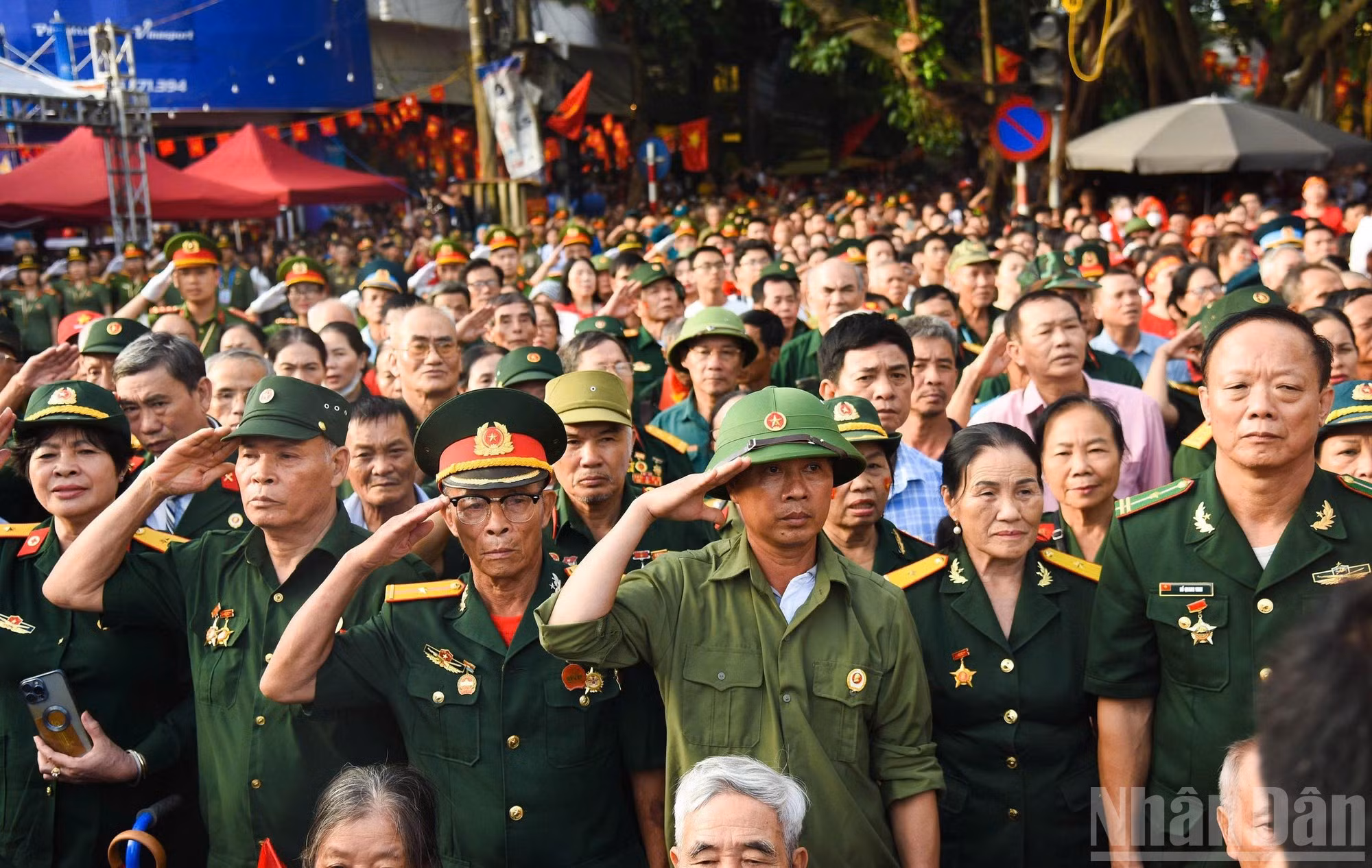 Los veteranos de guerra y la gente esperan en las calles por donde pasa el desfile militar y civil.