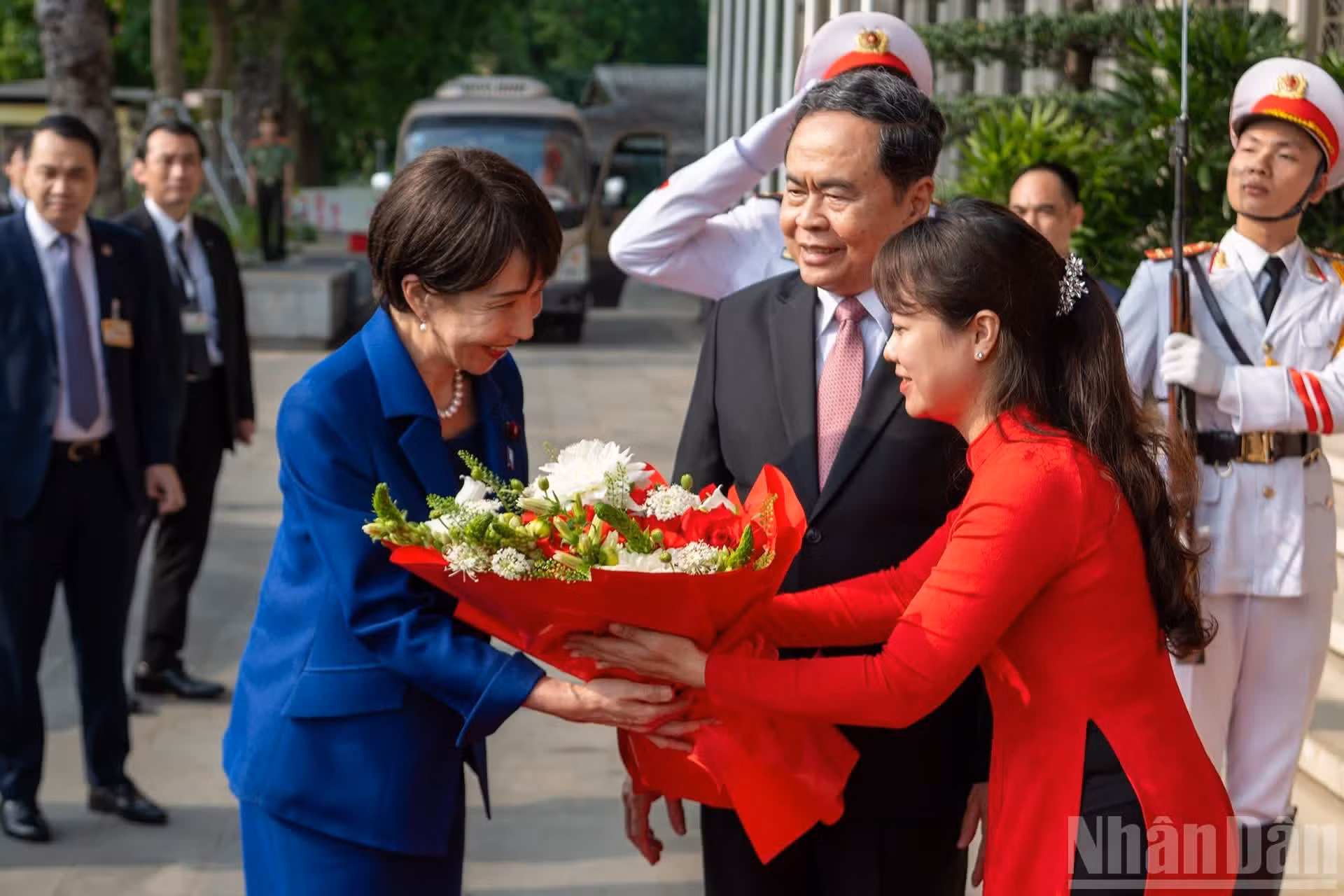 Funcionaria de la Oficina de la Asamblea Nacional entrega flores de bienvenida a la dirigente japonesa.