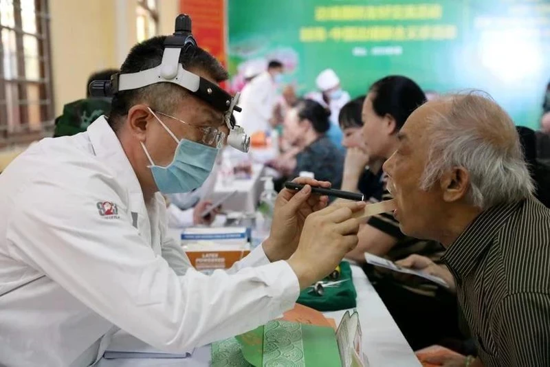 Un médico militar chino realiza chequeo a un poblador de la provincia de Lang Son (Foto: VNA)