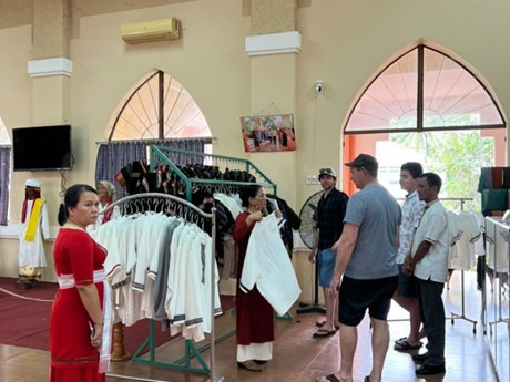 Visitantes extranjeros en una tienda de introducción de productos de brocado de la aldea artesanal de My Nghiep. (Foto: VOV)