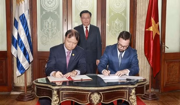 El presidente del Parlamento Vuong Dinh Hue en presencia de la firma de las actas del Comité conjunto de Cooperación Económica, Comercial y de Inversiones entre el ministro interino de Relaciones Exteriores de Uruguay, Nicolás Albertoni, (izquierda) y el viceministro de Industria y Comercio Do Thang Hai (Foto: VNA)