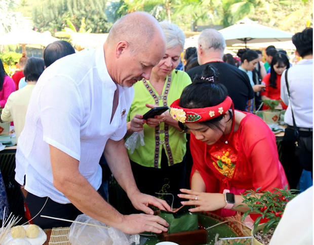 Los visitantes extranjeros experimentan la elaboración de Banh Chung. (Fotografía: dangcongsan.vn)