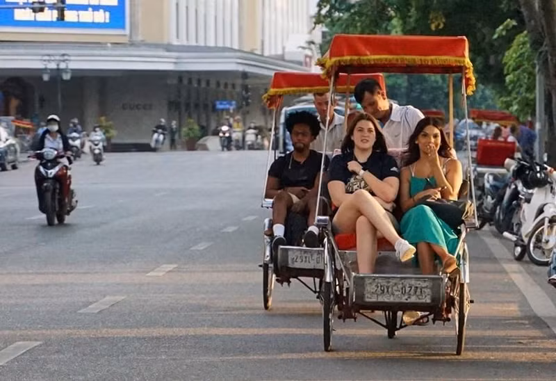 Turistas extranjeros experimentan triciclos alrededor del lago Hoan Kiem.