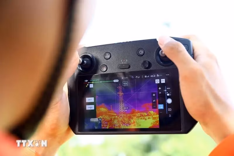 Un trabajador de transmisión eléctrica Binh Dinh utiliza un vehículo aéreo no tripulado (UAV) con una cámara termográfica para verificar la emisión de calor de los equipos en la línea eléctrica. (Fotografía: VNA)