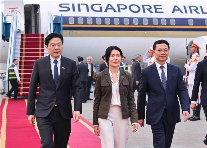 El ministro vietnamita de Ciencia y Tecnología, Nguyen Manh Hung, recibe al primer ministro de Singapur, Lawrence Wong, y su esposa en el aeropuerto de Noi Bai. (Fotografía: VNA)