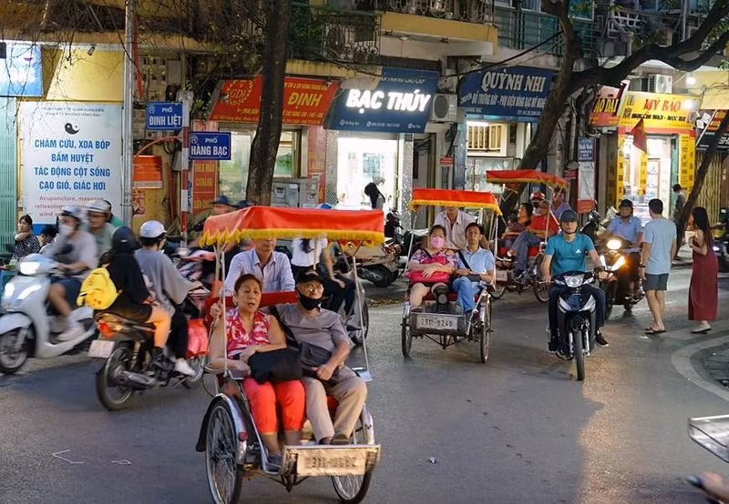 Turistas extranjeros visitan la calle de Dinh Liet en triciclos.