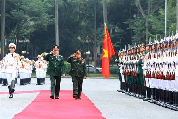 El jefe de la Dirección General de Política del Ejército Popular de Vietnam, Luong Cuong, y su homólogo laosiano, Thongloi Silivong, pasan revista a la guardia de honor. (Fotografía: VNA)