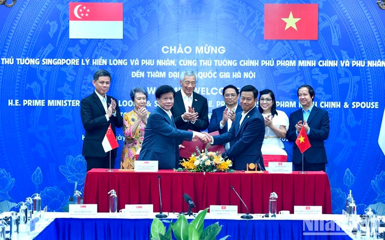 Los dos dirigentes testimonian la firma de un acuerdo de cooperación entre la Universidad Nacional de Hanói, la Universidad Nacional de Ciudad Ho Chi Minh y la Universidad Tecnológica Nanyang (Singapur). (Fotografía: VNA)