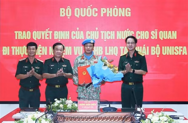 El viceministro de Defensa de Vietnam Hoang Xuan Chien entrega la Decisión del Presidente de Estado al primer coronel Dang Quoc Tuan. (Fotografía: VNA)