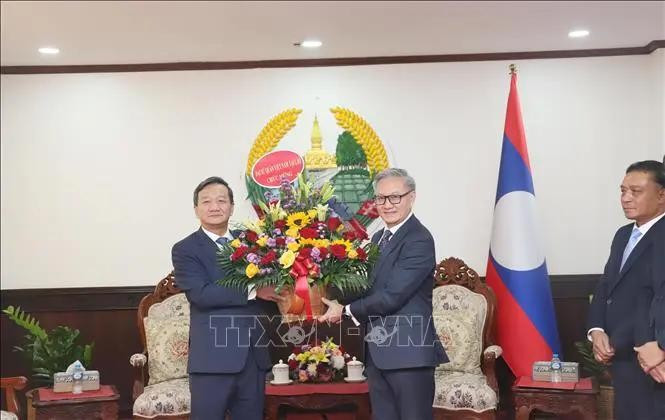 El embajador de Vietnam en Laos, Nguyen Minh Tam, entrega flores para felicitar el 49 aniversario del Día Nacional de Laos al ministro de Relaciones Exteriores de ese país, Thongsavanh Phomvihane. (Fotografía: VNA)