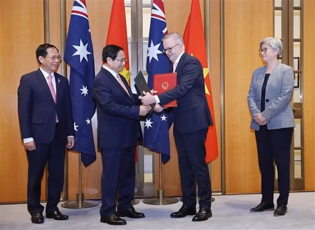 El primer ministro Pham Minh Chinh y su homólogo australiano Anthony Albanese presentan la Declaración Conjunta sobre la mejora de las relaciones a una Asociación Estratégica Integral. (Foto: VNA)