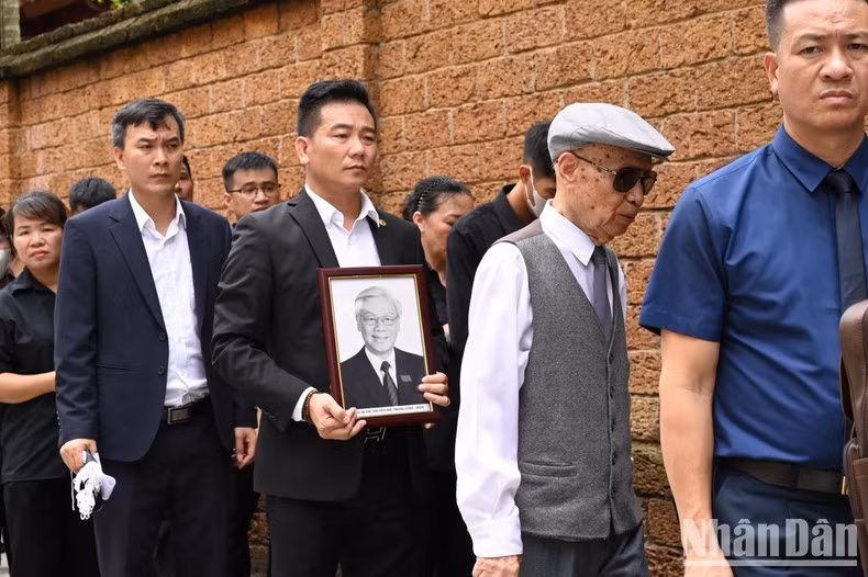 Muchas personas portan retrato del secretario general Nguyen Phu Trong.