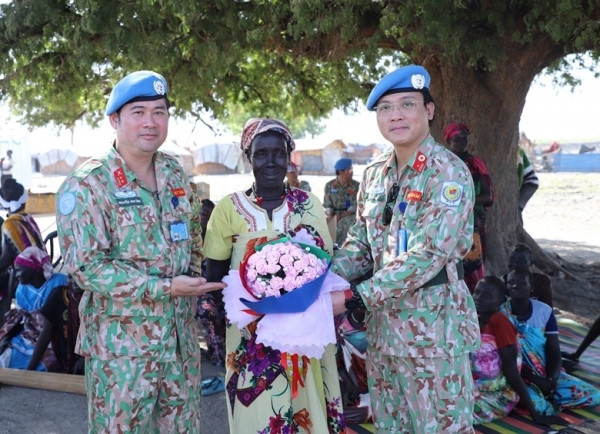 Representantes del hospital de campaña de segundo nivel número 4 de Vietnam regalan flores a una mujer sudsudanesa en ocasión del Día Internacional de la Mujer. 