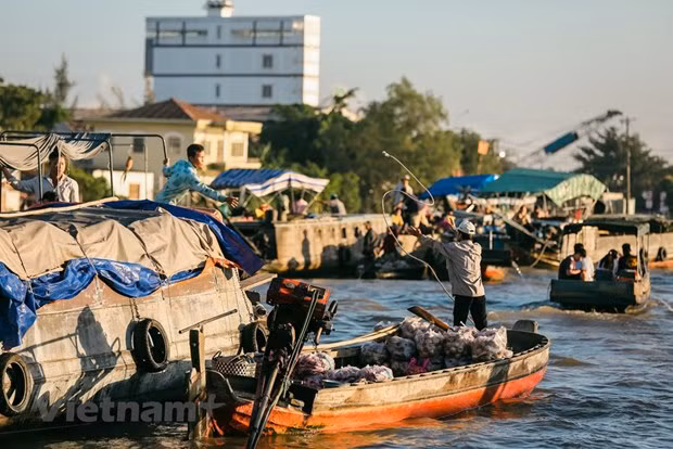 La gente comercia de barco en barco haciendo malabares o pasando artículos con la mano. (Fuente: Vietnam+) La gente comercia de barco en barco haciendo malabares o pasando artículos con la mano. (Fuente: Vietnam+)
