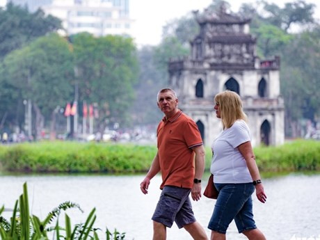 Turistas extranjeros pasean por el lago Hoan Kiem, en Hanói (Foto: tuoitre.vn)