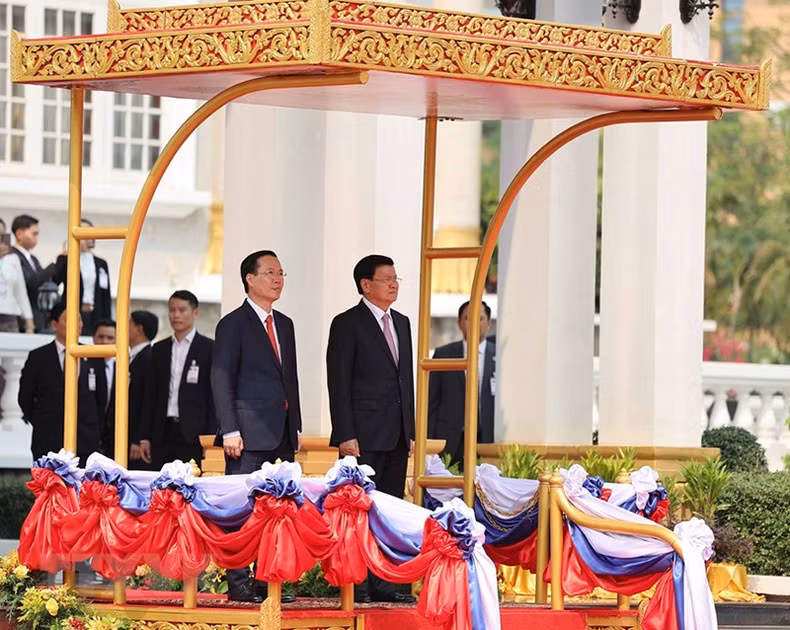 El secretario general PPRL y presidente de Laos, Thongloun Sisoulith, y el presidente Vo Van Thuong realizan acto del saludo a la bandera.