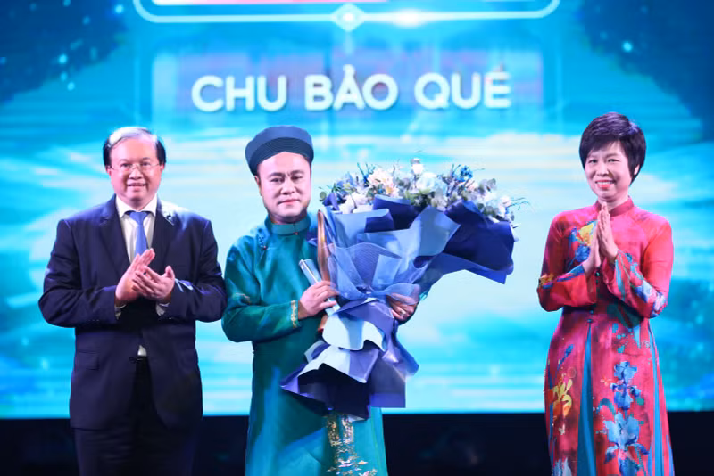 La directora general de la VNA, Vu Viet Trang (derecha), y el viceministro de Cultura, Deportes y Turismo, Ta Quang Dong (izquierda), entregan el premio de Artista inspirador a Chu Bao Que. (Foto: VNA)